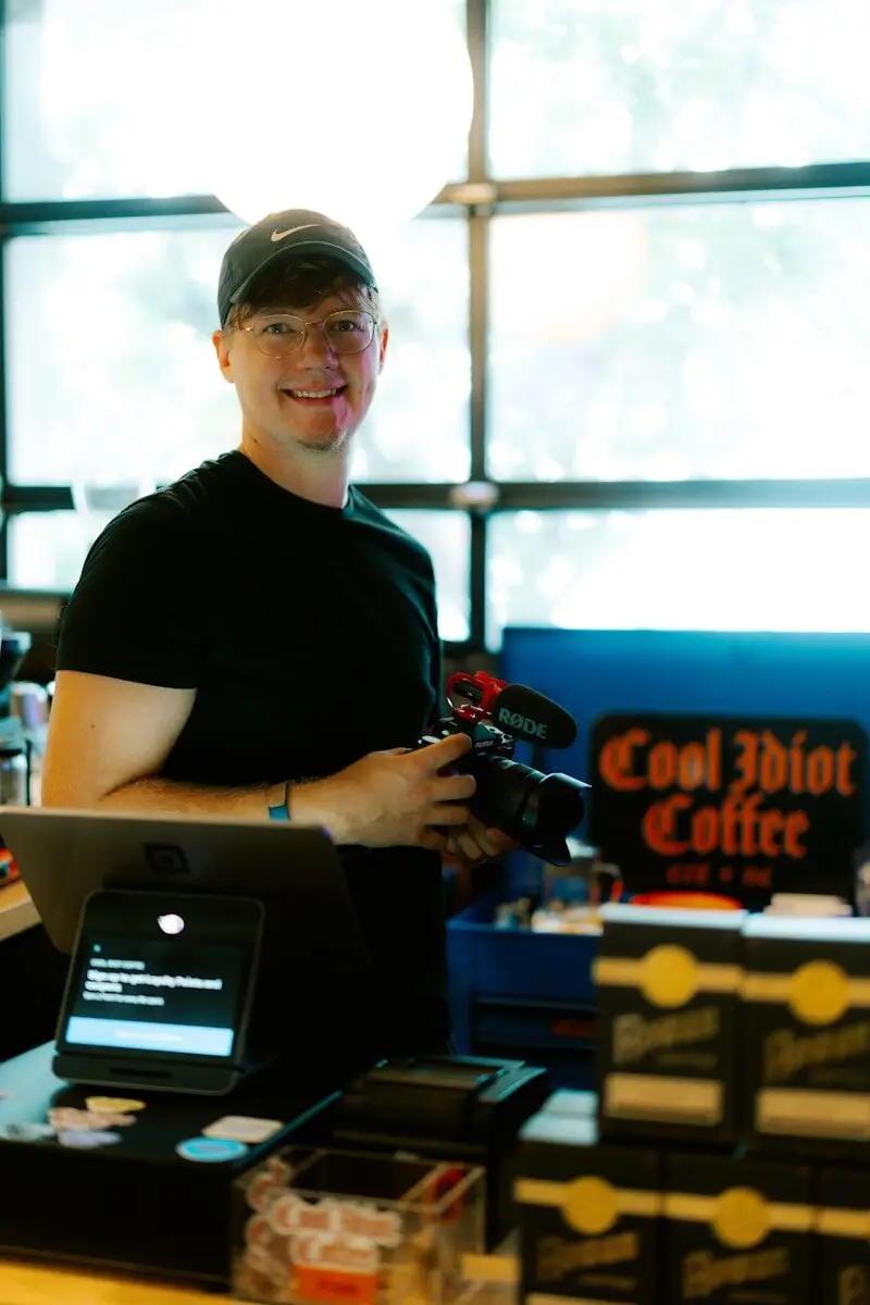 Man with camera stands behind coffee shop counter
